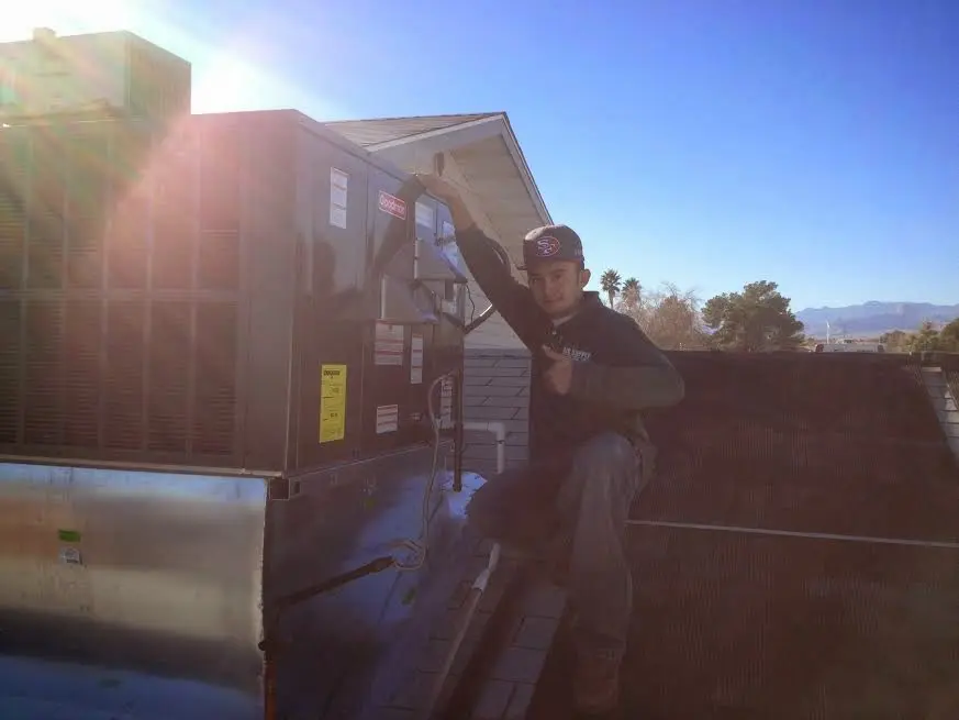 HVAC technician performing Air Duct Cleaning on a rooftop unit in Pflugerville